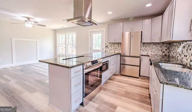 a kitchen with stainless steel appliances granite countertop a stove a sink and a refrigerator