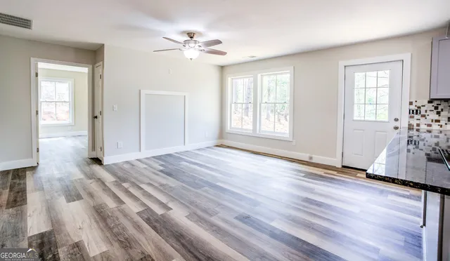 a view of empty room with wooden floor and fan