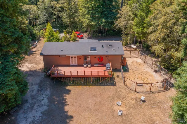 an aerial view of a house with swimming pool and large trees