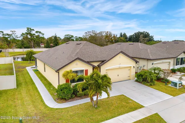 a view of a house with a big yard plants and large tree