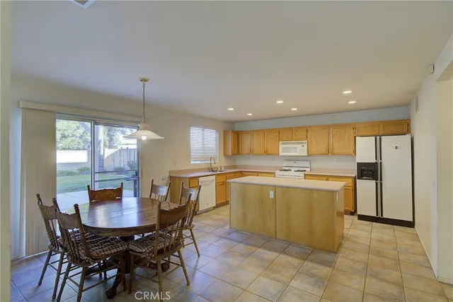 a kitchen with a dining table chairs and white appliances