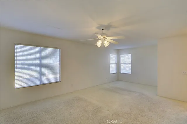 an empty room with windows and chandelier fan