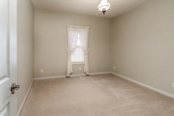 an empty room with a fireplace and chandelier