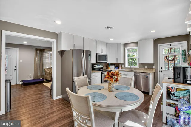 a kitchen with stainless steel appliances a dining table chairs and a refrigerator