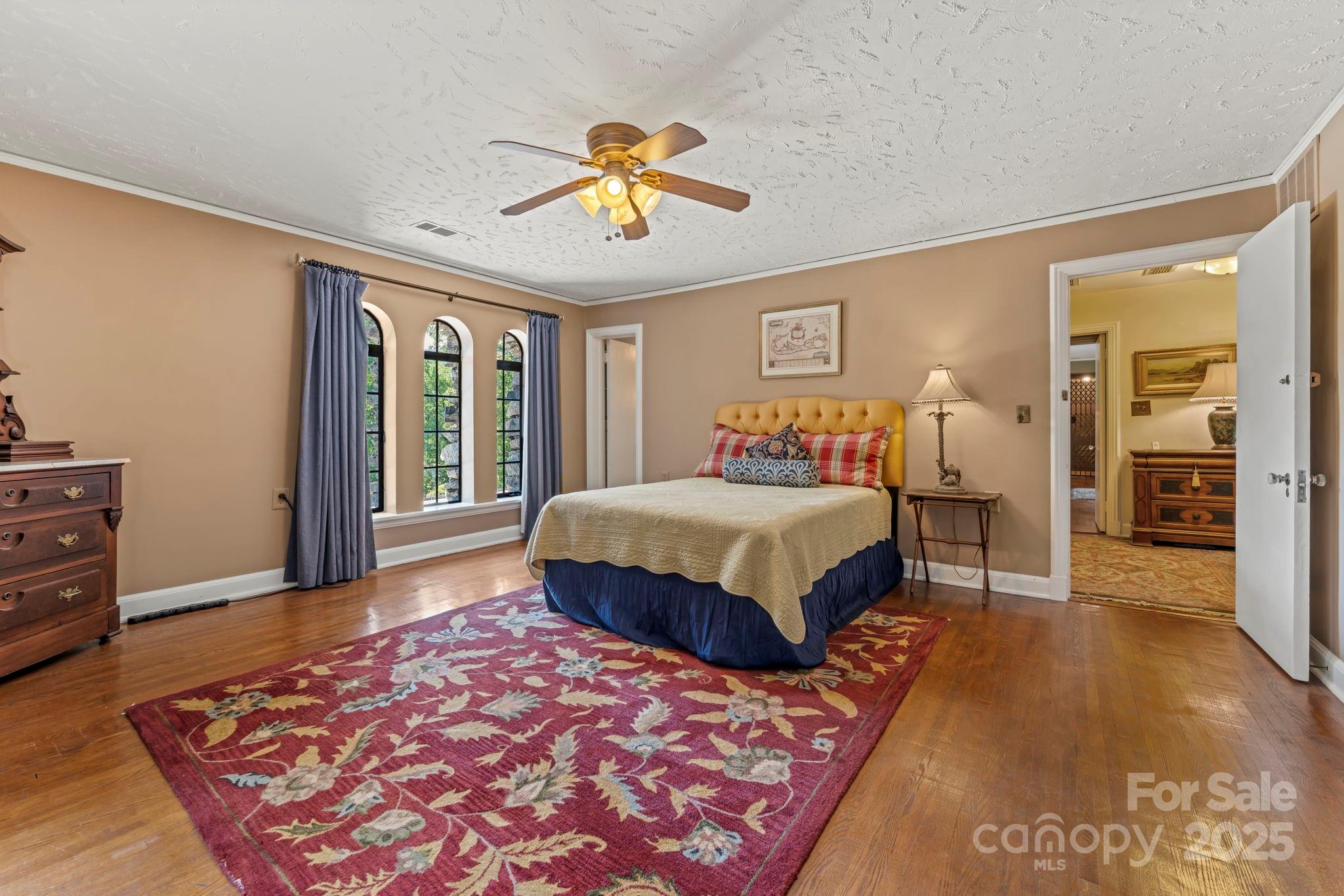 222 Stone Hedge Lane Tryon, NC 28782 - Photo 28 of 48 a spacious bedroom with a large bed and a chandelier