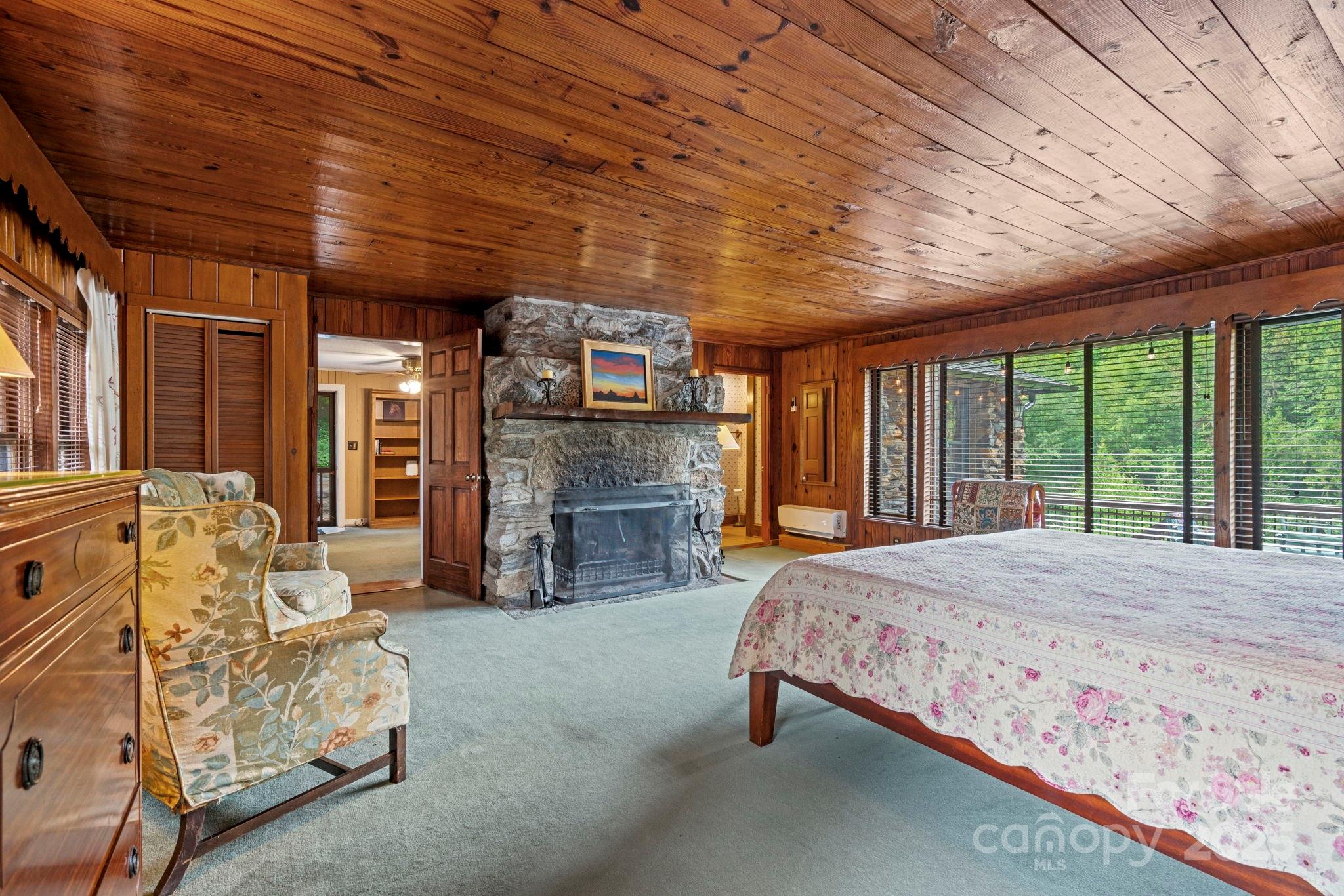 222 Stone Hedge Lane Tryon, NC 28782 - Photo 38 of 48 a spacious bedroom with a bed and a fireplace