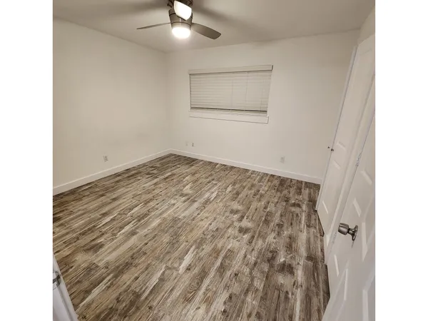 a view of a room with wooden floor and ceiling fan