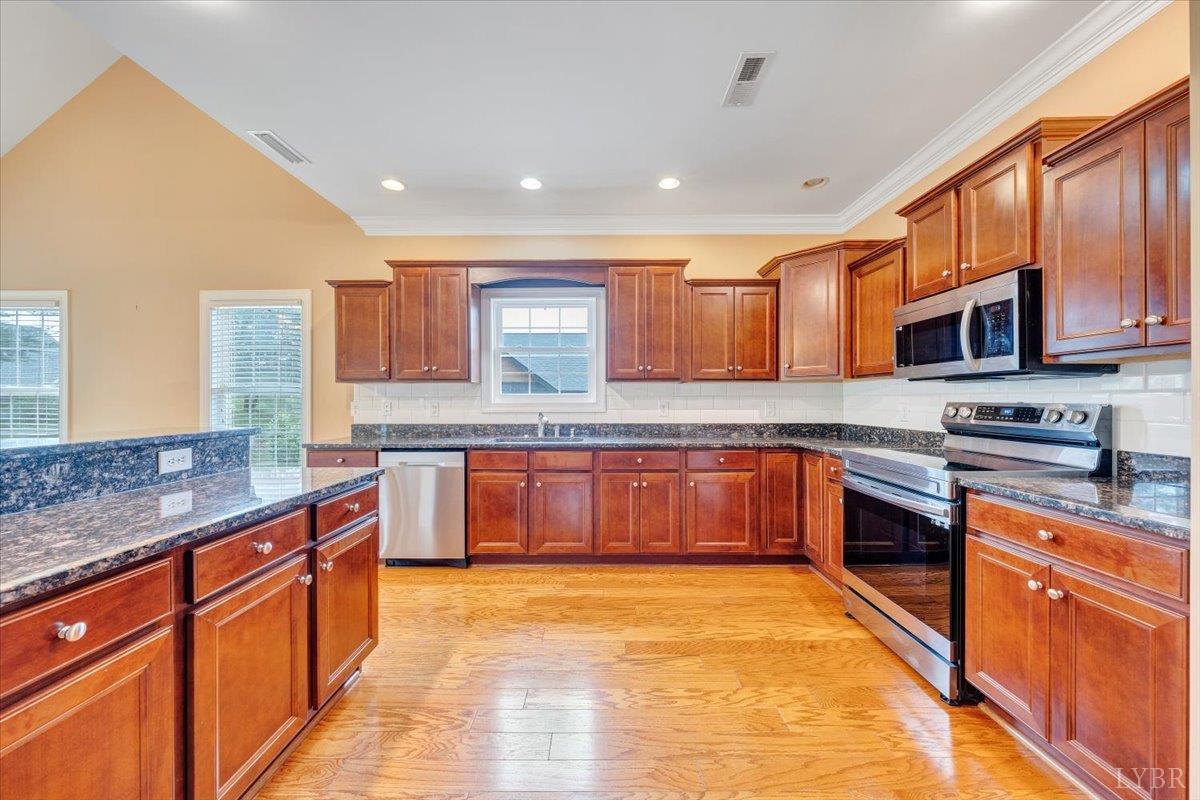 1250 Our Cove Road Huddleston, VA 24104 - Photo 18 of 70 a kitchen with stainless steel appliances granite countertop wooden cabinets a stove top oven a sink and dishwasher
