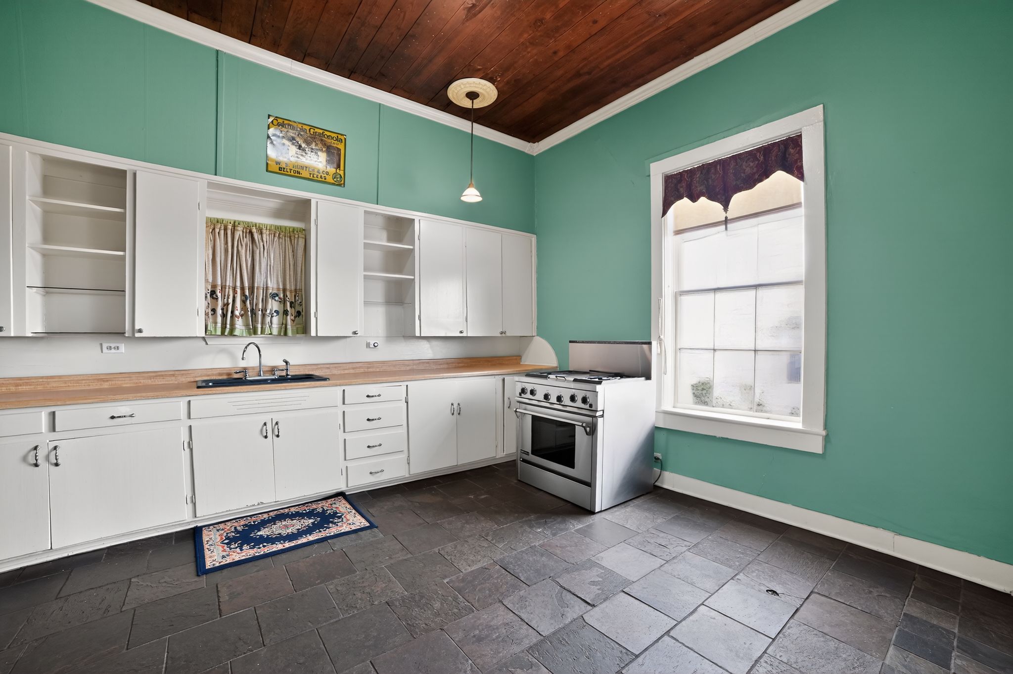 400 South Main Street Belton, TX 76513 - Photo 7 of 18 Kitchen featuring open shelves, white cabinetry, stone tile flooring, stainless steel stove, and ornamental molding