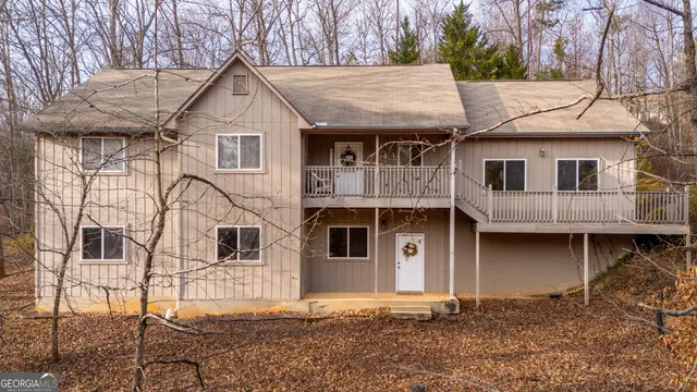 a view of a white house with large windows and a small yard