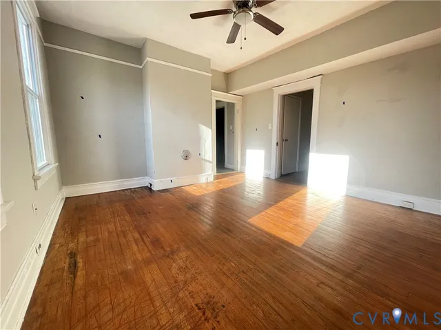 an empty room with wooden floor and windows