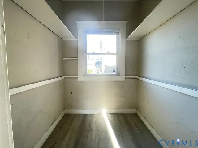 a view of empty room with wooden floor and fan