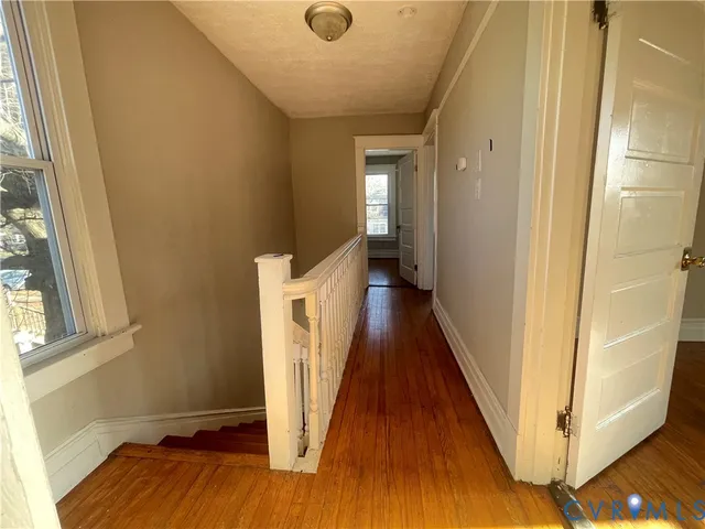a view of a hallway with wooden floor and staircase