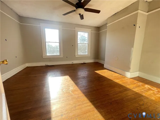a view of empty room with wooden floor and fan