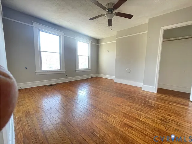 an empty room with wooden floor and windows