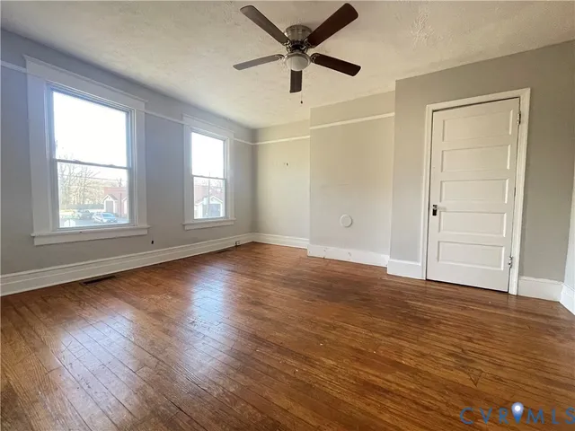 a view of empty room with wooden floor and fan