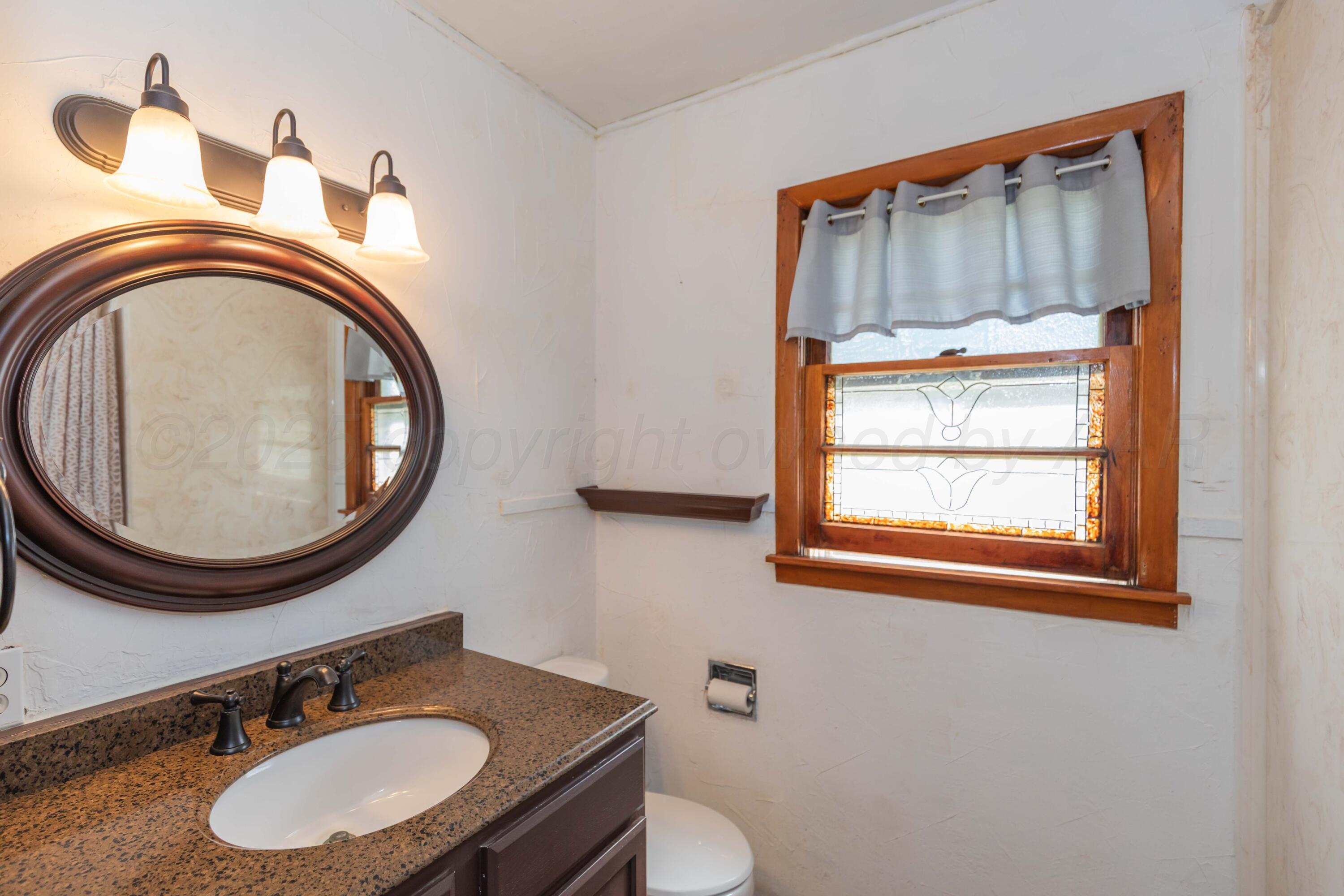 209 East 12th Street Wheeler, TX 79096 - Photo 25 of 40 a bathroom with a sink a mirror and a toilet