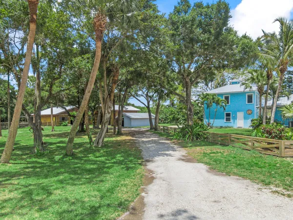 a view of a house with a big yard and large trees