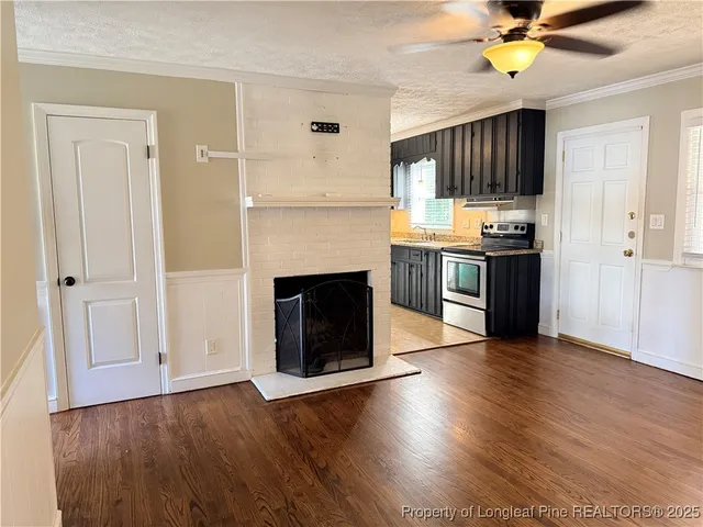 a living room with stainless steel appliances wooden floors and fireplace
