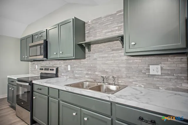 a kitchen with stainless steel appliances granite countertop white cabinets sink and microwave