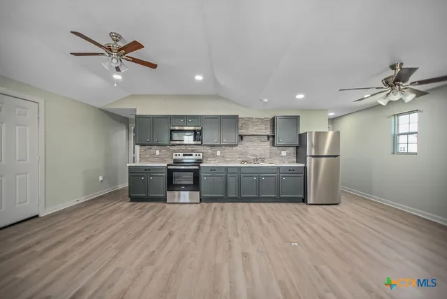 a kitchen with stainless steel appliances a sink cabinets and wooden floor