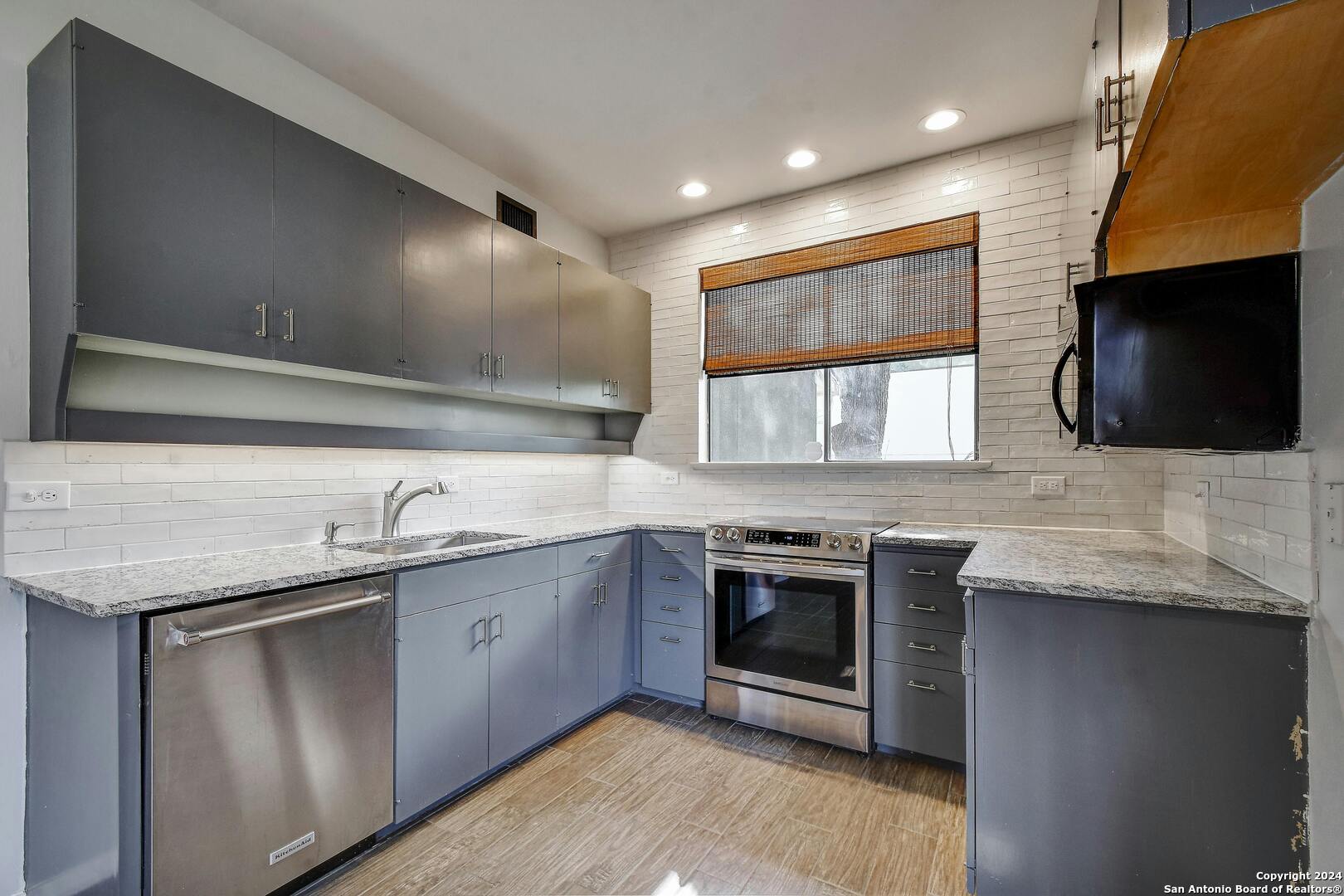 143 Terrell Road, Unit 1/2 San Antonio, TX 78209 - Photo 13 of 31 a kitchen with stainless steel appliances granite countertop a sink and a stove top oven with wooden floor
