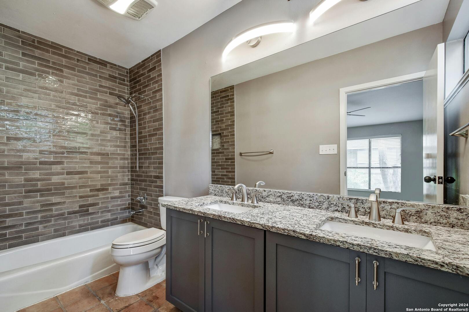 143 Terrell Road, Unit 1/2 San Antonio, TX 78209 - Photo 22 of 31 a bathroom with a granite countertop toilet a sink a mirror a shower a vanity and a window