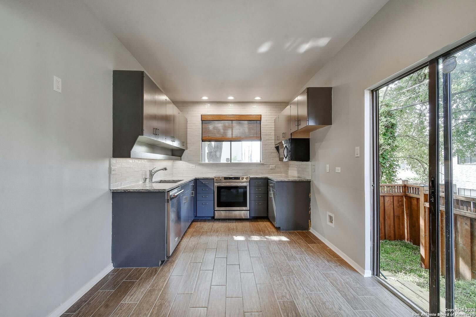 143 Terrell Road, Unit 1/2 San Antonio, TX 78209 - Photo 7 of 31 a large kitchen with stainless steel appliances granite countertop a stove and a wooden floors