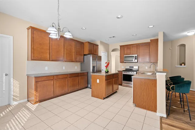 a kitchen with stainless steel appliances granite countertop a refrigerator a stove top oven a sink dishwasher and wooden cabinets