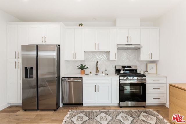 a kitchen with stainless steel appliances granite countertop a refrigerator sink and stove