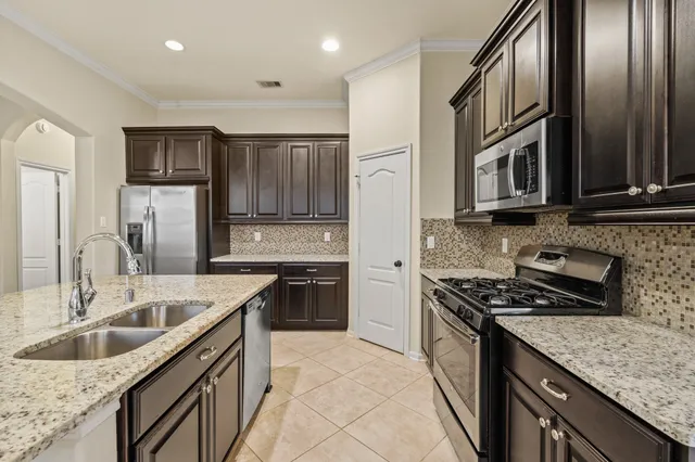 a kitchen with stainless steel appliances granite countertop a sink stove microwave and refrigerator