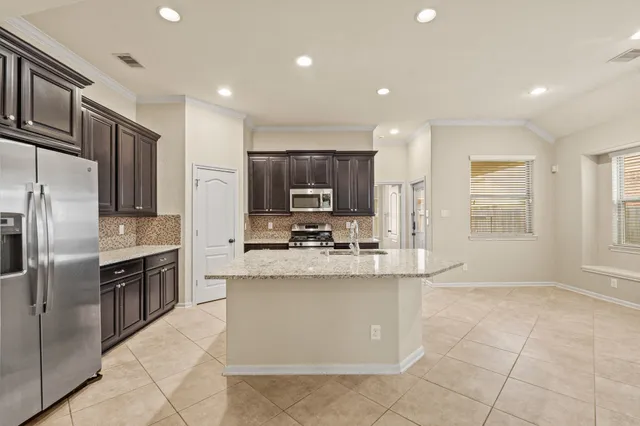 a kitchen with stainless steel appliances granite countertop a stove top oven a sink and a refrigerator