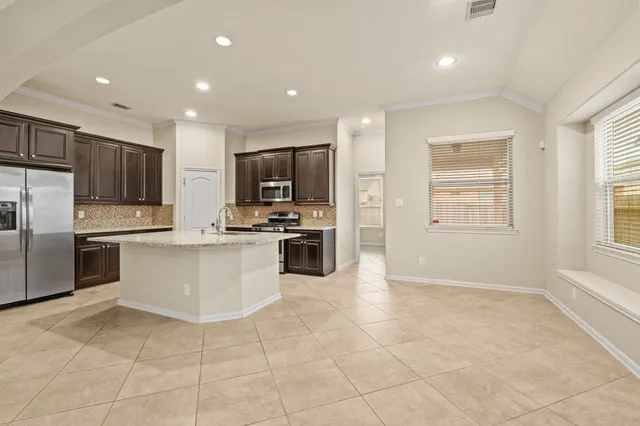 a kitchen with granite countertop a refrigerator and a stove top oven