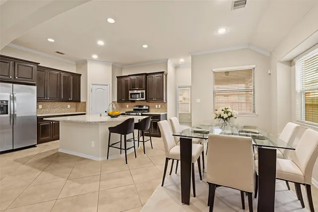 a kitchen with a table chairs refrigerator microwave and cabinets