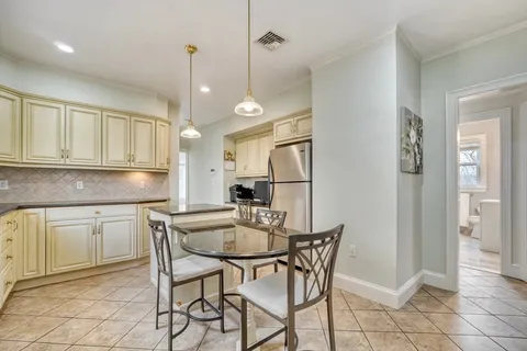 a kitchen with stainless steel appliances granite countertop a dining table chairs and white cabinets