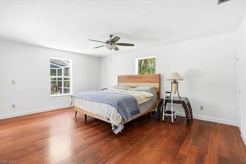 a bedroom with a bed a window and wooden floor