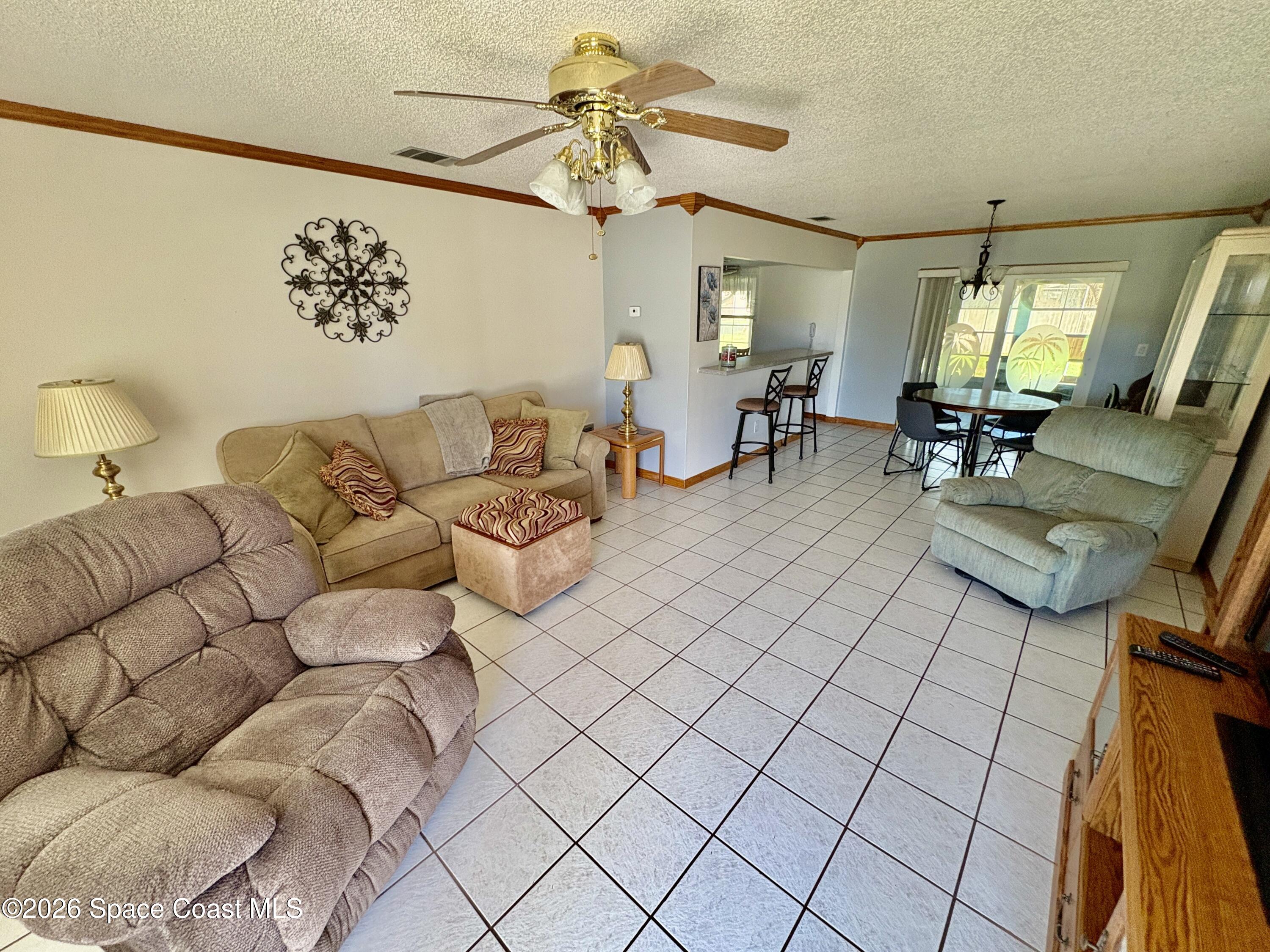 585 Crystal Mist Road Northwest Palm Bay, FL 32907 - Photo 6 of 21 a living room with furniture and a chandelier