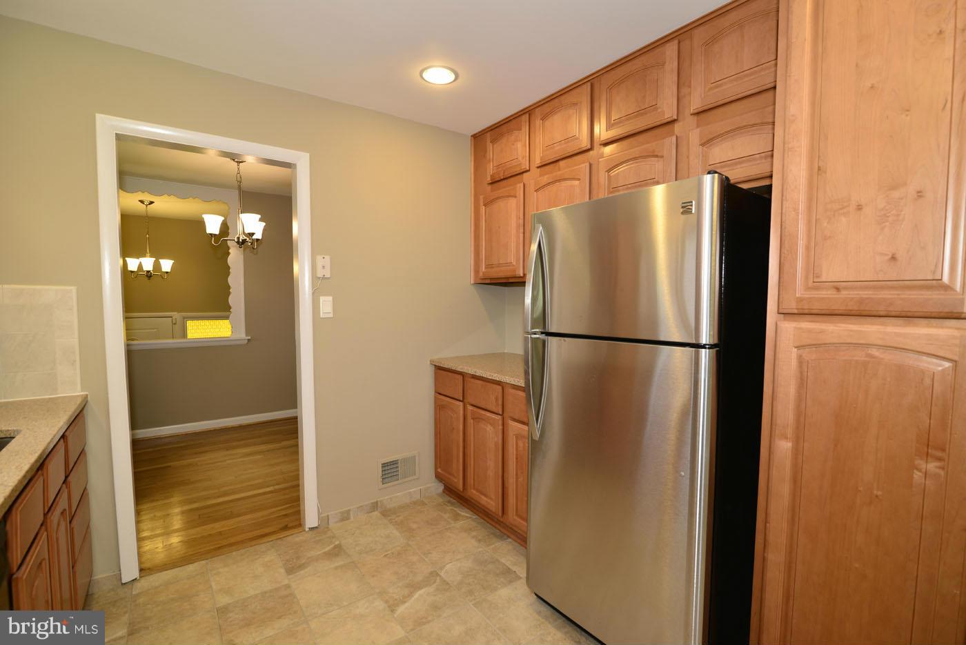 7115 Kerr Drive Springfield, VA 22150 - Photo 10 of 25 a view of a refrigerator in kitchen and an empty room in wooden floor