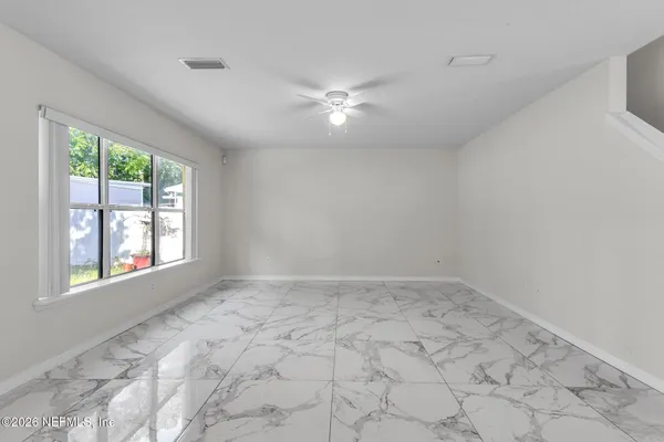 an empty room with windows and ceiling fan