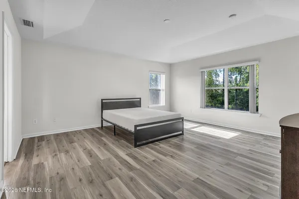 a spacious bedroom with a bed and wooden floor