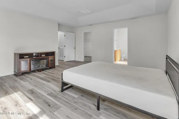 a spacious bedroom with a bed and wooden floor