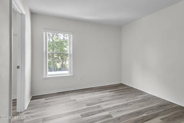 an empty room with wooden floor and windows
