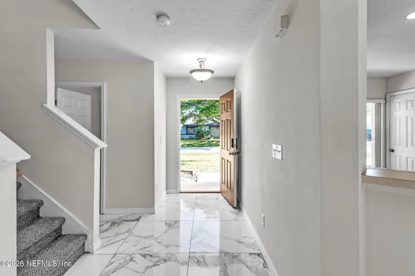 a view of a hallway to an empty room with wooden floor and a bathroom