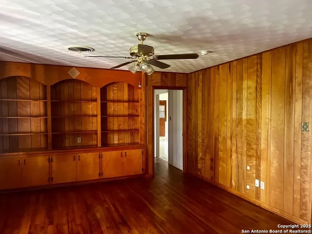 a view of empty room with wooden floor and fan