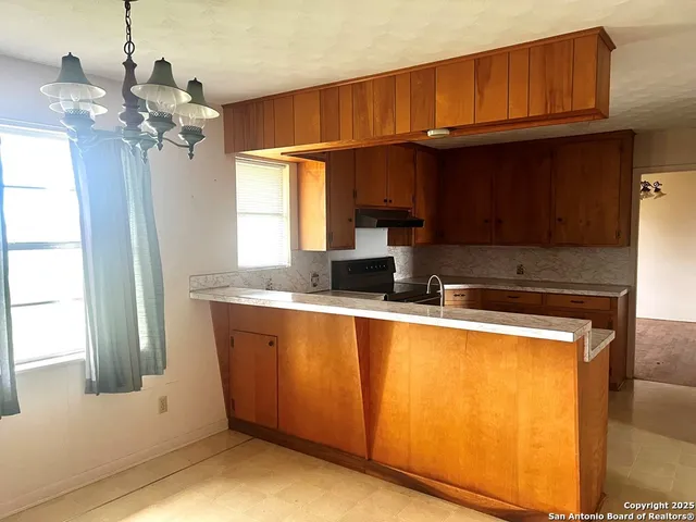 a kitchen with a sink appliances cabinets and a window