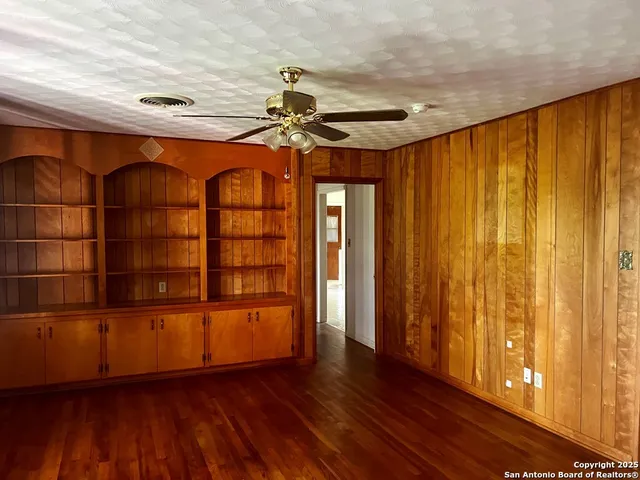 a view of empty room with wooden floor and fan