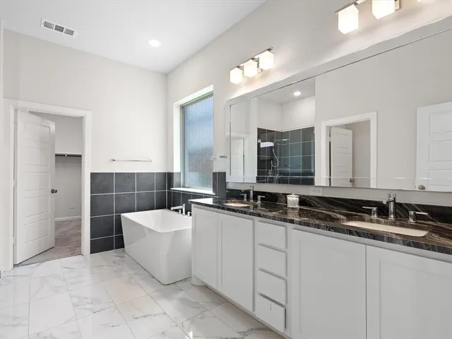 a bathroom with a tub a sink and mirror