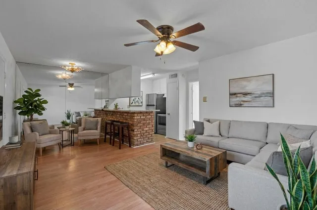 a living room with furniture kitchen view and a potted plant