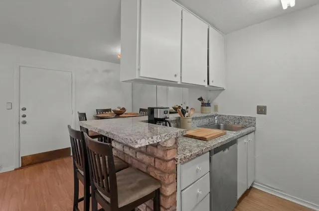 a kitchen with stainless steel appliances granite countertop a table chairs sink and cabinets