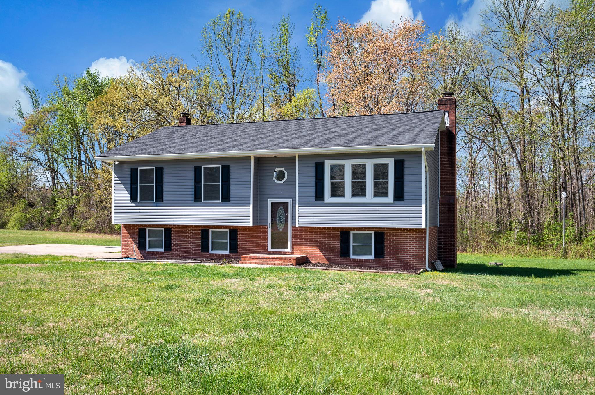 13452 Post Oak Road Spotsylvania, VA 22551 - Photo 6 of 56 a view of a brick house with a big yard and large trees